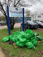 Piles of green trash bags next to Twincraft Skincare sign