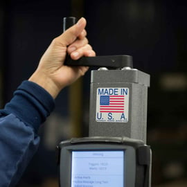 Twincraft Skincare employee hand holding machine lever with "Made in U.S.A" sticker