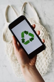 hand holding phone which shows the recycling logo